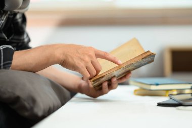 Genç adam kanepede dinleniyor ve kitap okuyor. Hafta sonları evde boş vakit geçiriyor..