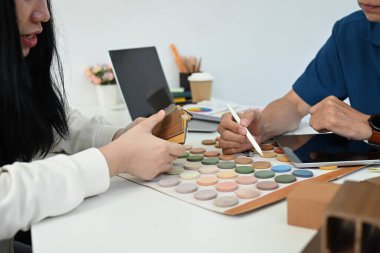 Arkadaş canlısı üst düzey erkek tasarımcı, müşterisinin iç dekorasyon için renk paleti seçmesine yardım ediyor..