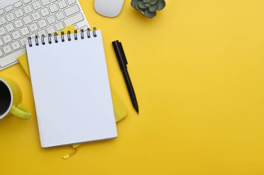 Laptop, not defteri, kahve fincanı ve sarı arka plan mali raporları. Kopyalama alanı olan üst görünüm.