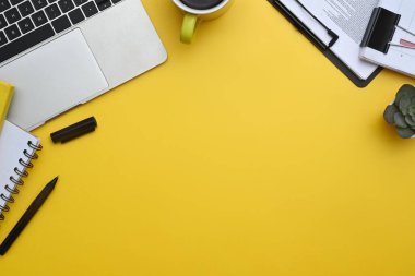 Laptop, not defteri, kahve fincanı ve sarı arka plan mali raporları. Kopyalama alanı olan üst görünüm.