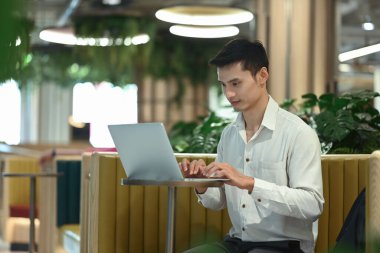 Modern çalışma alanında dizüstü bilgisayarla çalışan yakışıklı bir iş adamı..