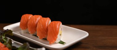 Uramaki suşisi ya da Kaliforniya somon rulosu ahşap masada servis edilir. Japon yemek tarzı konsept.