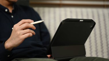 Evdeki kanepede oturup dijital tablet kullanan genç işadamını kapat..