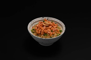 Tasty Japanese fried rice or Yakimeshi topped with salmon and spring onion on black background. clipart