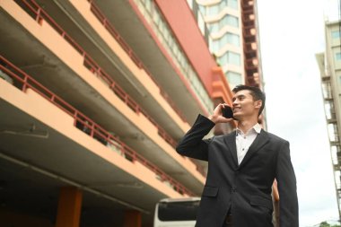 Düşük açılı, zarif iş adamı telefon görüşmesi yapıyor. Şehir caddesinde dikiliyor, başka tarafa bakıyor..