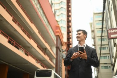 Şehir caddesinde akıllı telefon kullanan yakışıklı iş adamının portresi..