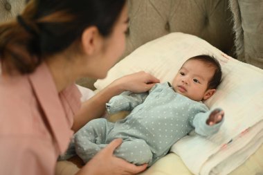 Sevimli yeni doğmuş bebek annesiyle birlikte yumuşak kanepede yatıyor. Annelik ve çocuk bakımı kavramı.