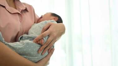 Güzel, genç Asyalı bir anne oturma odasında yeni doğmuş bir bebeği taşıyor. Aşk anı ve anneler günü konsepti.