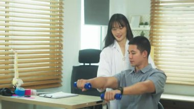 Asyalı hasta terapist rehberliğinde ağırlık kaldırıyor. Rehabilitasyon ve sağlık hizmeti kavramı.