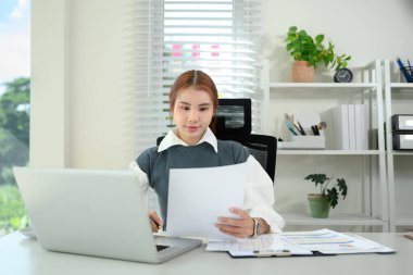 Genç girişimcinin ofiste dizüstü bilgisayarla ve finansal belgeyle çalışırken vurulması.