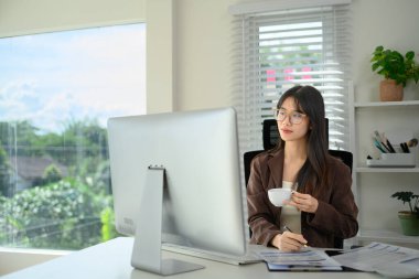 Kahve içen ve ofisinde çalışan Asyalı kadın girişimcinin portresi..