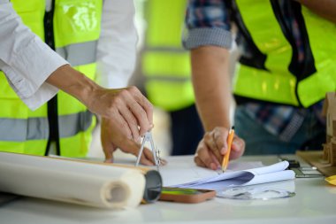 İnşaat alanındaki projeleri gözden geçiren yansıtıcı ceketler giyen mühendis ekibi.