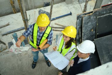 İnşaat işçileri ekibi ve iş adamı inşaat alanındaki projeyi tartışıyorlar..