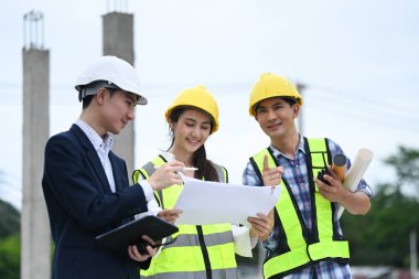 İnşaat işçileri ekibi ve iş adamı inşaat alanındaki projeyi tartışıyorlar..