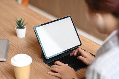 Kafede dijital tabletle çalışan kablosuz klavyede yazan iş kadınının omzunun üstünden bak.