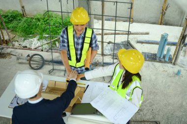 İnşaat alanında müteahhit ve mimar ekibinin el ele tutuşmalarının genel görünümü.