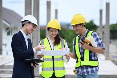 Mühendislik ekibi inşaat alanında dururken planı tartışıyor..
