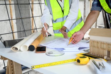 Şantiyedeki inşaat planıyla ilgili planlar yapan kırpılmış bir mimar takımı..