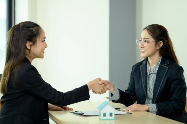 Finansal danışman ya da emlakçı, satın alma anlaşması imzaladıktan sonra müşterisiyle tokalaşıyor.