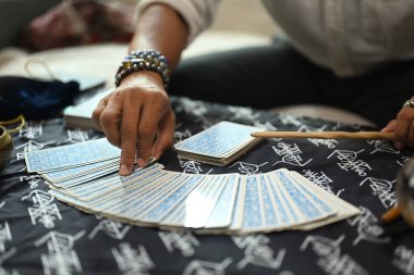 Yakından bakınca falcının tarot kartı seçtiğini görüyoruz. Tahmin ve kehanet kavramı.