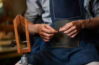 Deri ustası, iğneyle deri dikiyor. Küçük işletme ve el yapımı konsept.