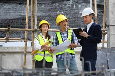 Uzmanlardan oluşan bir ekip inşaat alanındaki projeyi tartışıyor.