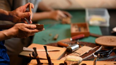 Deri kemerli deneyimli bir zanaatkarın atölyesinde çekim yaparken yakın plan çekimi..