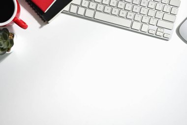 Üst görünüm bilgisayar klavyesi, defter ve kahve fincanı beyaz masada. Metin için alanı kopyala.