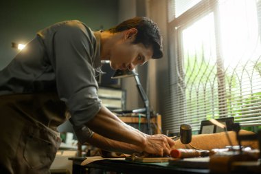 Yetenekli bir zanaatkar atölyesinde bir deri parçasını dikkatle işaretliyor..