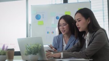 Birlikte çalışan profesyonel iş kadınları çalışma alanındaki proje istatistiklerini analiz ediyorlar.