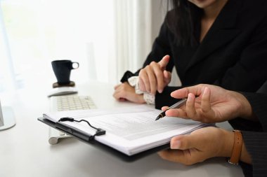 Modern bir ofiste bir belgeyi inceleyen iki profesyonel iş kadını..