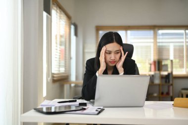 Modern bir ev ofisinde dizüstü bilgisayarı üzerinde çalışırken stres yaşayan bir iş kadını..