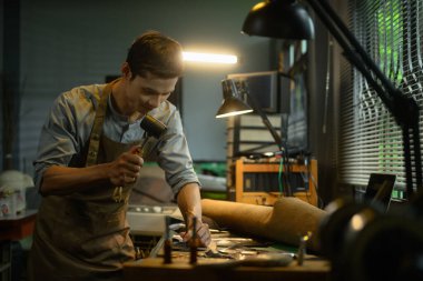 Profesyonel bir zanaatkar, çekiç ve diğer aletlerle deri parçayı şekillendirir ve detaylandırır..