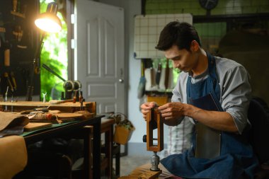 Genç deri ustası deri parçaları dikkatlice dikiyor. Küçük işletme ve el yapımı konsept