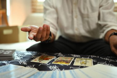 Falcı, masada mistik bir bezle tarot kartları okuyor. Tahmin ve kehanet kavramı.