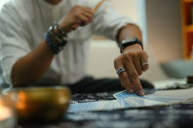 Kapalı görüşlü falcı gizemli bir bezle kaplı bir masada rastgele tarot kartı seçiyor..