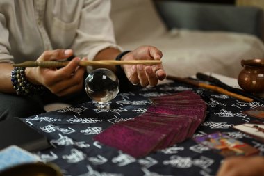 Falcı, mistik bezlerle kaplı bir masanın üzerine Tarot kartları seriyor. Öngörü kavramı.
