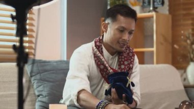 Falcı, çevrimiçi oturumu tahmin ederken akıllı telefon kamerasının önünde tahta rünleri gösteriyor.