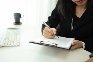 Gülümseyen Asyalı kadın çalışan işyerindeki belgeleri inceliyor..