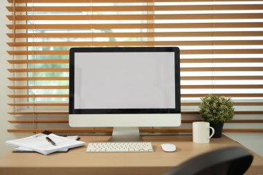 Minimalist ev ofisi. Tahta masadaki boş ekranlı bilgisayar monitörünün ön görüntüsü.
