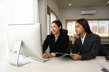 İki gülümseyen iş arkadaşı birlikte yeni bir proje üzerinde çalışıyorlar..