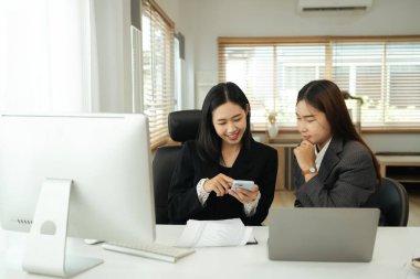 Neşeli ve gülümseyen genç iş arkadaşları işe ara veriyorlar ve cep telefonu kullanıyorlar..