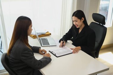 İki iş kadını mali muhasebe belgelerini tartışıyor, ofiste birlikte çalışıyorlar..