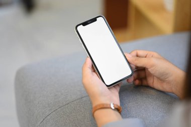 Kadın ellerinin beyaz ekranlı cep telefonunu tutarken, evdeki kanepede uzanırken yakın plan çekimleri..