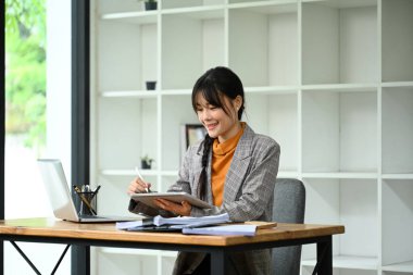 Modern bir ofiste dijital tabletini ve laptopunu kullanan Asyalı bir girişimci..