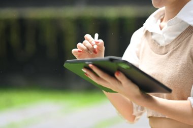 Modern ofis binasının dışında dijital tablet kullanan genç bir kadının görüntüsü..