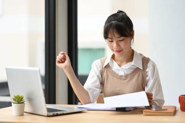 Güzel Asyalı üniversite öğrencisi dizüstü bilgisayar kullanıyor ve evrak işleriyle uğraşıyor..