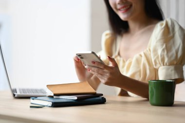 Ofis masasında otururken cep telefonuna mesaj yazan genç kadını kapat..