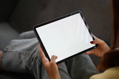 Evdeki kanepede oturan beyaz ekranlı dijital tabletli bir kadının yakın plan fotoğrafını çek..