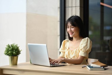 Güzel Asyalı genç bir kadın Kafe 'de dizüstü bilgisayarıyla online satış pazarlaması yapıyor..